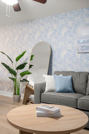 Un salon moderne avec un canapé gris, une table basse ronde en bois et une plante en pot.