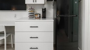 Una cocina compacta con un armario blanco, un refrigerador negro y un microondas en la encimera.