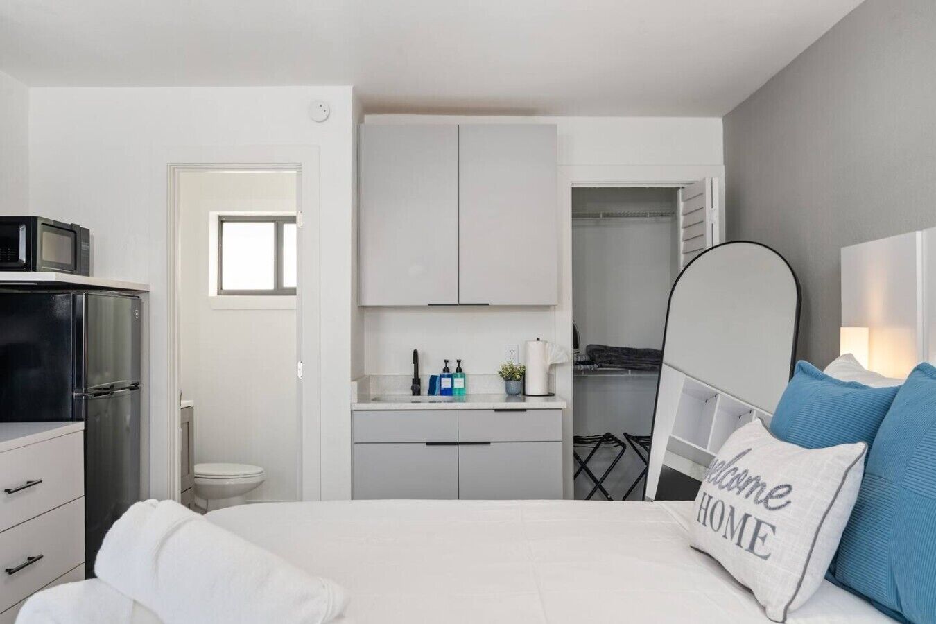 Une chambre à coucher avec un lit, une table de chevet, une armoire et une salle de bain visible à travers une porte ouverte.