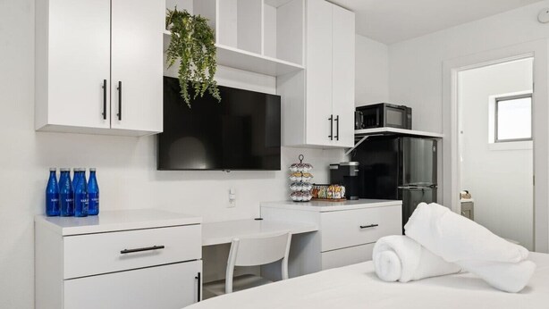 Una habitación de hotel moderna con cama, escritorio, televisor, microondas y refrigerador.