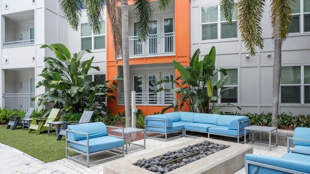 A courtyard with outdoor seating, a fire pit, and a building with balconies. - Luxury Palm Retreat - HUGE 2BR 2BA near Downtown (Tampa)
