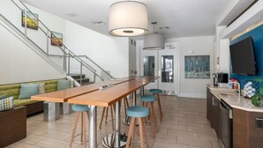 A modern kitchen with a wooden bar, bar stools, a staircase, and a dining area with a sofa. - Luxury Palm Retreat - HUGE 2BR 2BA near Downtown (Tampa)