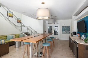 Eine moderne Küche mit einer Holzbar, Barhocker, einer Treppe und einem Essbereich mit einer Couch.