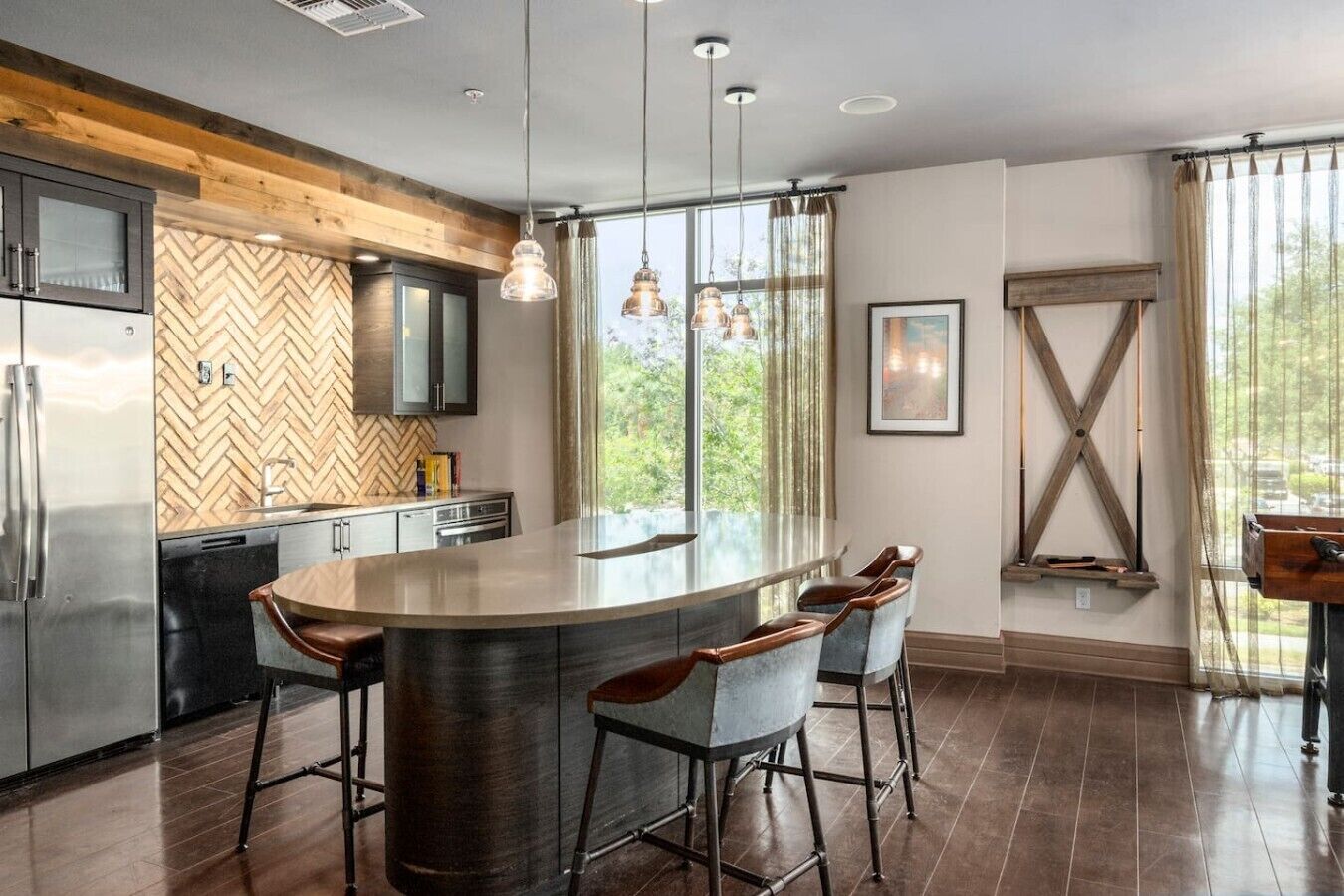 A modern kitchen with a central island, bar stools, and a herringbone-patterned backsplash.