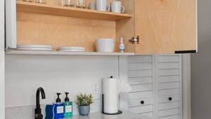 A compact kitchen with wooden shelves, a sink, and a countertop. - Cozy Studio: BBQ, Dining & Relaxing Vibes (Tampa)