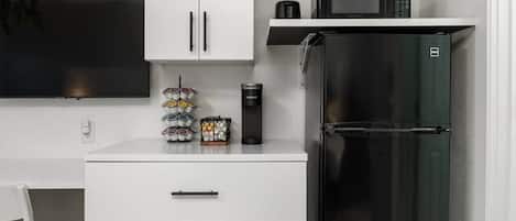 A compact kitchen with a white cabinet, a black refrigerator, and a microwave on the countertop.