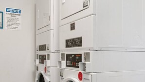A laundry room with two stacked front-loading washing machines, a notice board with laundry room rules, and a control panel on the machines. - Stylish Studio w/ BBQ & Outdoor Oasis (Tampa)