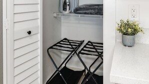 A closet with a hanging rack, a shelf with a striped item, and a potted plant on a countertop. - Stylish Studio w/ BBQ & Outdoor Oasis (Tampa)