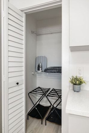A closet with a hanging rack, a shelf with a striped item, and a potted plant on a countertop. - Stylish Studio w/ BBQ & Outdoor Oasis (Tampa)