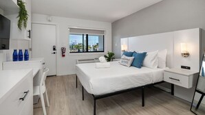 A modern bedroom with a bed, bedside tables, a desk, and a window. - Stylish Studio w/ BBQ & Outdoor Oasis (Tampa)