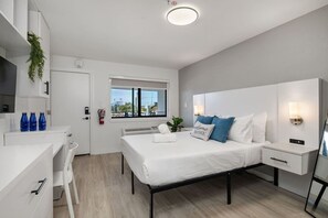 A modern bedroom with a bed, bedside tables, a desk, and a window. - Stylish Studio w/ BBQ & Outdoor Oasis (Tampa)