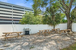 An outdoor patio area with picnic tables, a barbecue grill, and a white fence. - Stylish Studio w/ BBQ & Outdoor Oasis (Tampa)