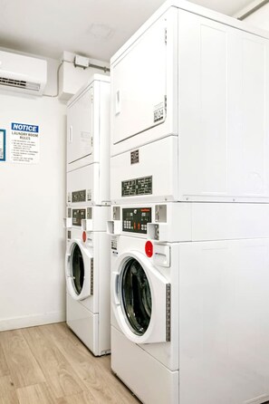 A laundry room with stacked washing machines and a notice board with laundry rules. - Modern Style Studio Apartment By Tampa (Tampa)
