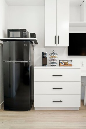 A kitchen with a black refrigerator, white cabinets, and a microwave on top. - Modern Style Studio Apartment By Tampa (Tampa)