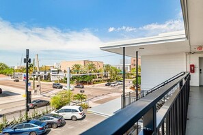 A balcony with a view of a busy intersection, a fire extinguisher, and a building entrance.