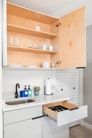 A compact kitchen with a built-in sink, a countertop with a faucet, a coffee maker, and a cabinet with a drawer. - Modern Style Studio Apartment By Tampa (Tampa)