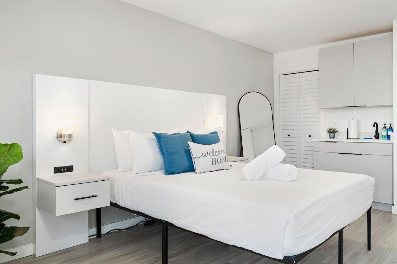 Une chambre d’hôtel moderne, équipée d’un lit, d’une table de chevet, d’une petite table et d’un grand miroir.