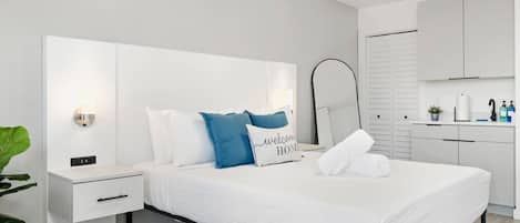 Una habitación de hotel moderna con una cama, mesita de noche y un espejo grande.