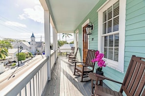 A porch with wooden rocking chairs and a potted orchid. - SombreroReef Light Suite (Key West)