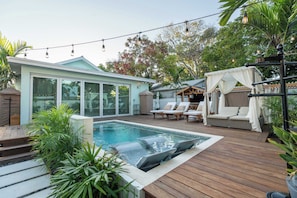 A pool area with a hot tub, lounge chairs, and a covered seating area. - Sombrero Reef Light Suite (Key West)