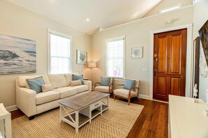 A living room with a beige sofa, two armchairs, a coffee table, and a wooden door. - Sombrero Reef Light Suite (Key West)