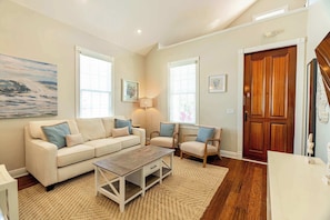 A living room with a sofa, chairs, a coffee table, and a wooden door. - SombreroReef Light Suite (Key West)