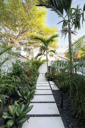 A pathway leading through a lush garden with various plants and trees. - SombreroReef Light Suite (Key West)