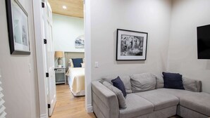 Uma sala de estar moderna com um sofá modular cinzento, uma fotografia a preto e branco emoldurada na parede e chão de madeira.