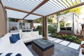 A covered outdoor seating area with a sofa, a coffee table, and a pergola. - The Lighthouse Group Suite (Key West)