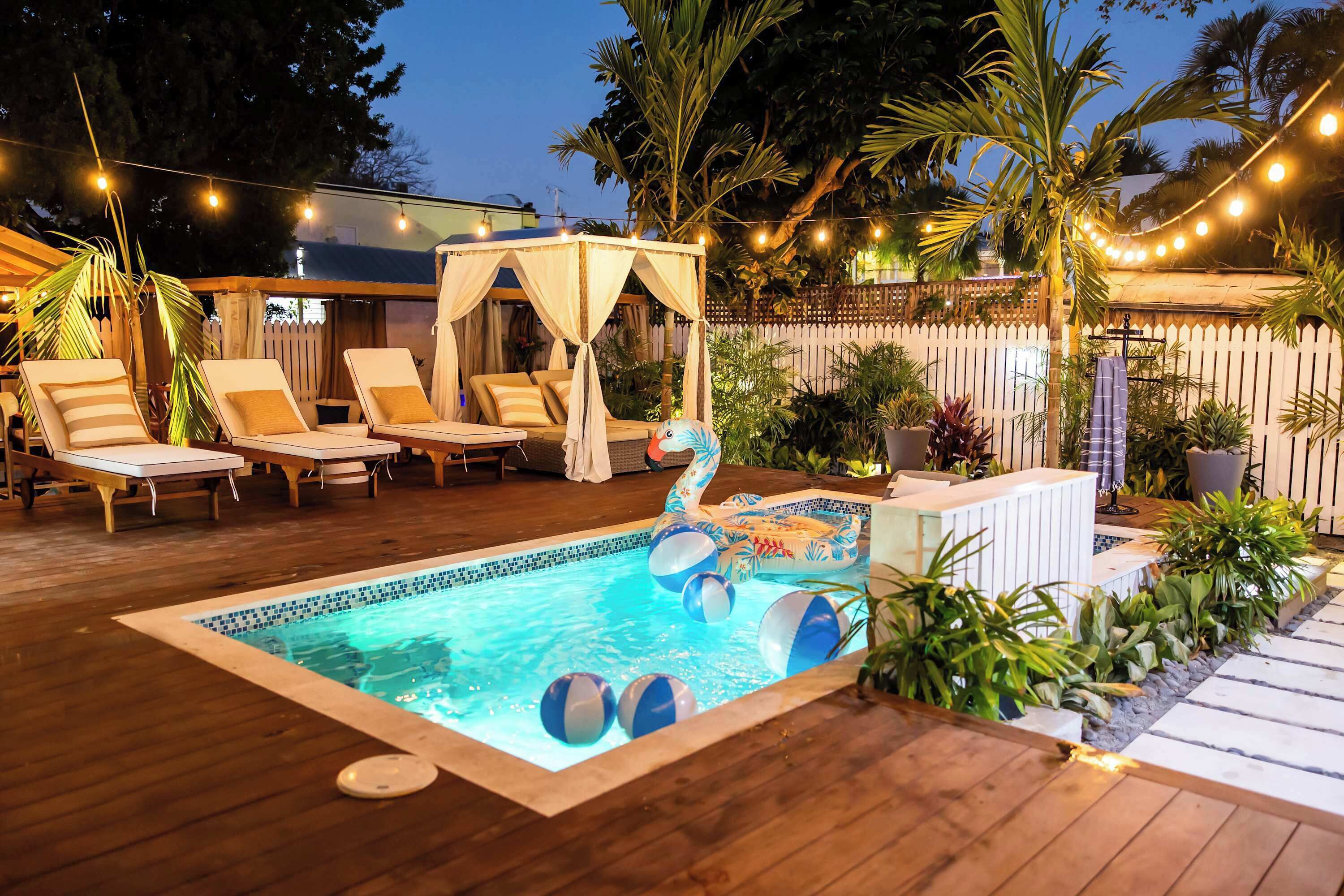 Un espace piscine aménagé avec des chaises longues, un auvent et une petite piscine gonflable avec des ballons de plage.