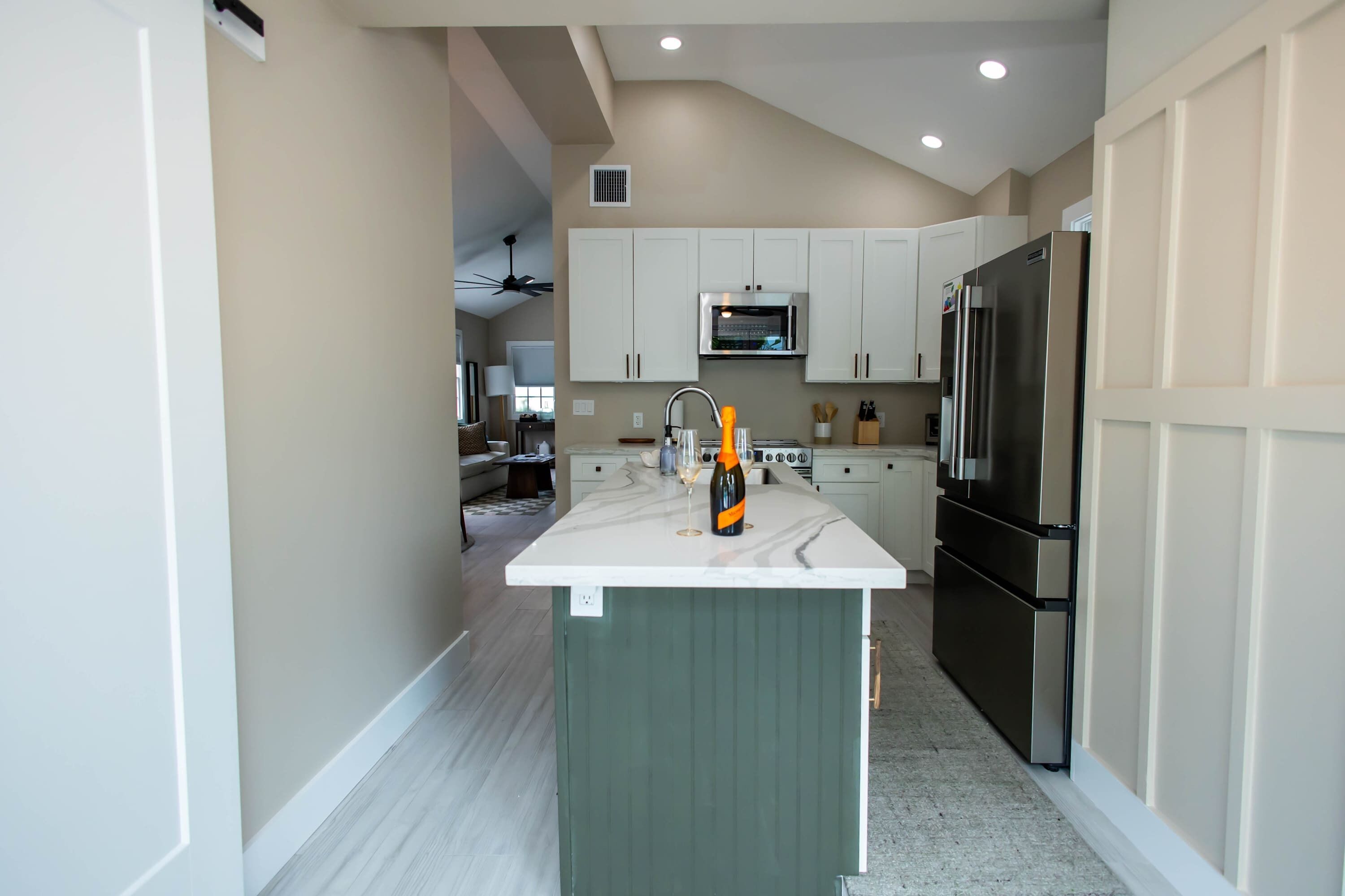 A modern kitchen with white cabinets, a central island, and stainless steel appliances.