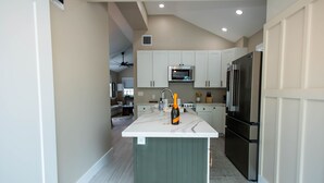 Una cocina moderna con armarios blancos, una isla central y electrodomésticos de acero inoxidable.
