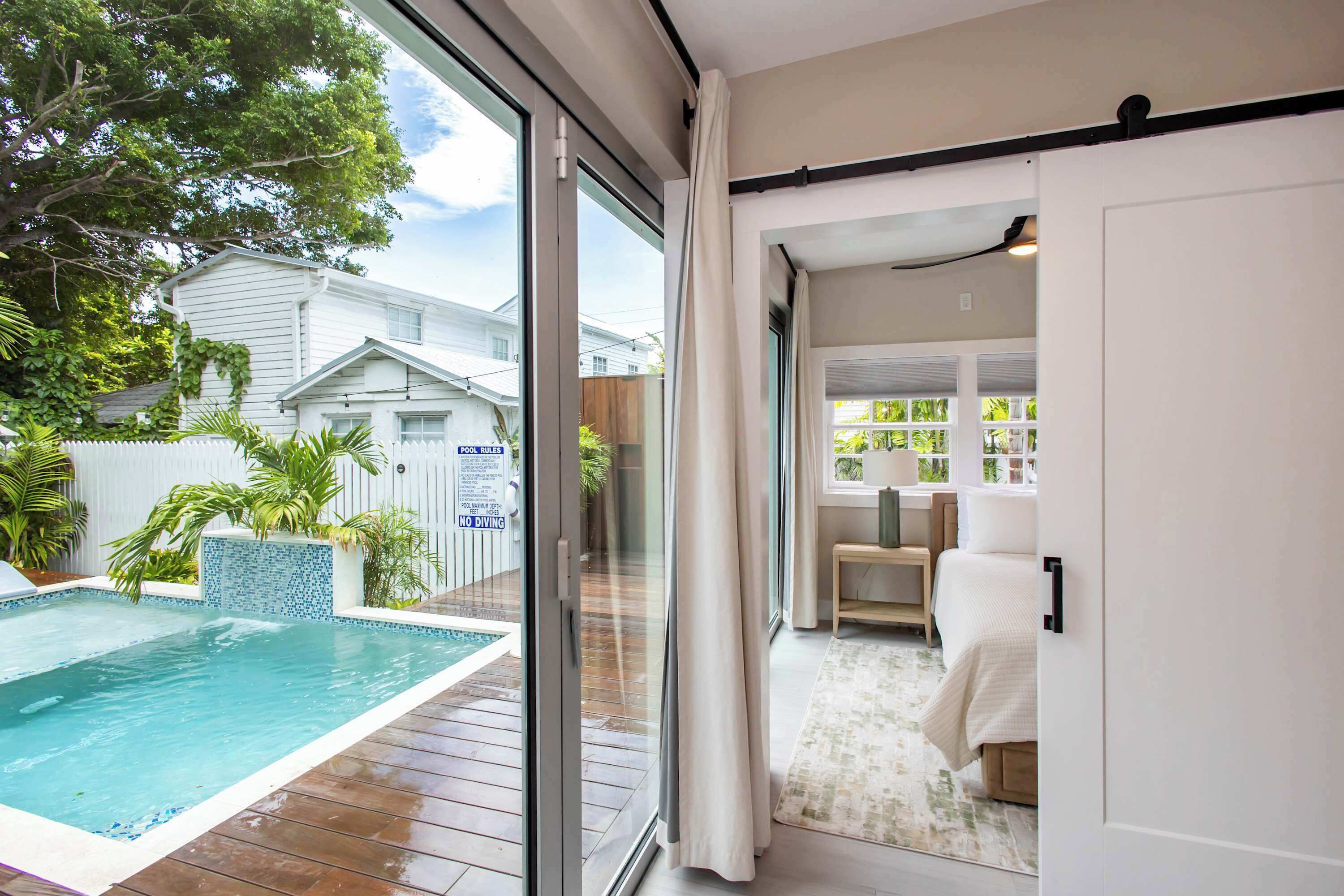 Ein modernes Haus mit Glastür zu einem Poolbereich und einem Schlafzimmer.