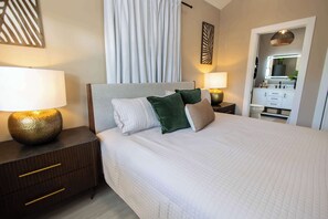 A hotel room with a bed, nightstands, a dresser, and a bathroom visible through an open door. - Carysfort Reef Light Suite (Key West)