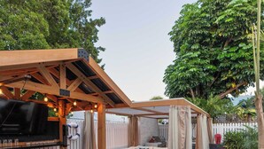 Un patio al aire libre con zona de barbacoa, asientos y un sendero de piedra.