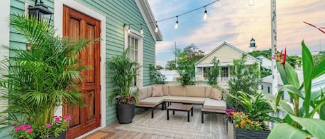 Un patio con un sofá, una mesa de centro y plantas en macetas.
