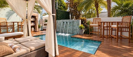 A pool area with a wooden deck, lounge chairs, and a waterfall feature.
