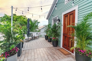 Eine überdachte Terrasse im Freien mit Holzdeck, Blumentöpfen und Lichterketten.
