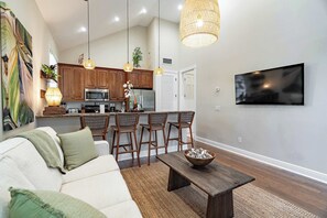 A modern living room with a sofa, coffee table, and bar stools. - TortugasHarbor Light Suite (Key West)