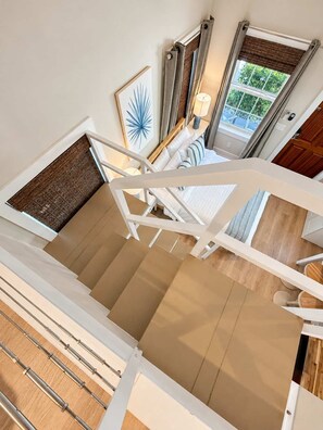 Eine Treppe mit Blick auf ein Schlafzimmer und ein Fenster mit Vorhängen.