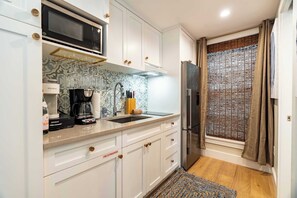 A compact kitchen with white cabinetry, a microwave, a coffee maker, and a refrigerator. - Key West Light Suite (Key West)