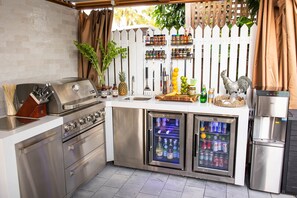 A compact kitchen with a built-in grill, two stainless steel refrigerators, and a variety of condiments and beverages. - Key West Light Suite (Key West)