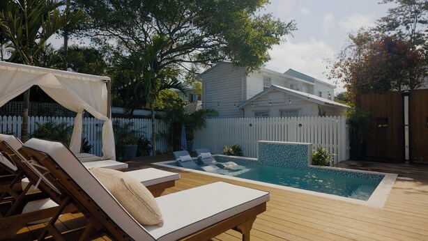 A backyard with a swimming pool, lounge chairs, and a covered seating area. - Key West Light Suite (Key West)