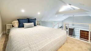 A bedroom with a sloped ceiling, a bed with a white quilt, and a view of a balcony. - Key West Light Suite (Key West)