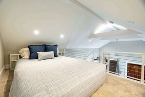 A bedroom with a sloped ceiling, a bed with a white quilt, and a view of a balcony. - Key West Light Suite (Key West)