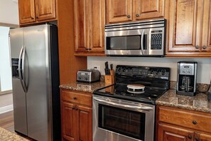 A kitchen with stainless steel appliances, wooden cabinets, granite countertops, and a built-in oven. - Alligator Reef Light Suite (Key West)