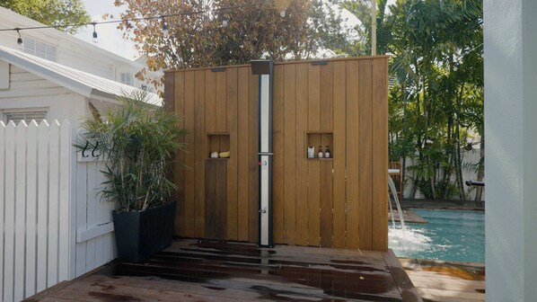 A wooden gate with a vertical handle, a white picket fence, and a pool in the background. - Alligator Reef Light Suite (Key West)