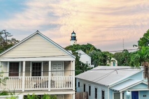 A coastal building with a balcony, a lighthouse in the background, and surrounding greenery. - The Lighthouse Penthouse Suite (Key West)