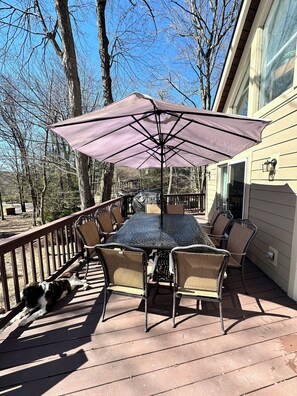 A deck with a table and chairs, a dog lying on the deck, and a house in the background. - Stunning Chalet 5-bedroom house in peaceful Lake Harmony with AC (Lake Harmony)