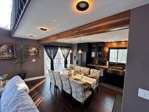 Et moderne spiseområde med træloft, et spisebord dækket til fire personer, og et køkken, der kan ses gennem en åben dør.